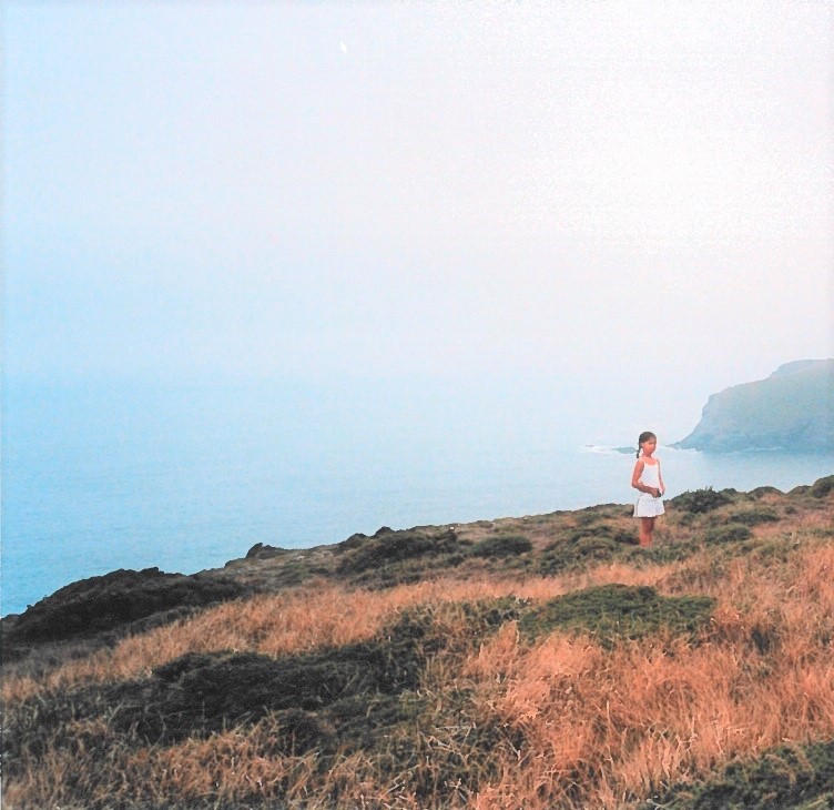Histoire d'une marche en plein ciel — Une petite fille se tient dos à la mer au bord d'une falaise.